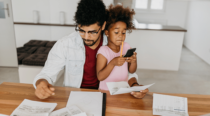 father filling out papers with daughter on his lap